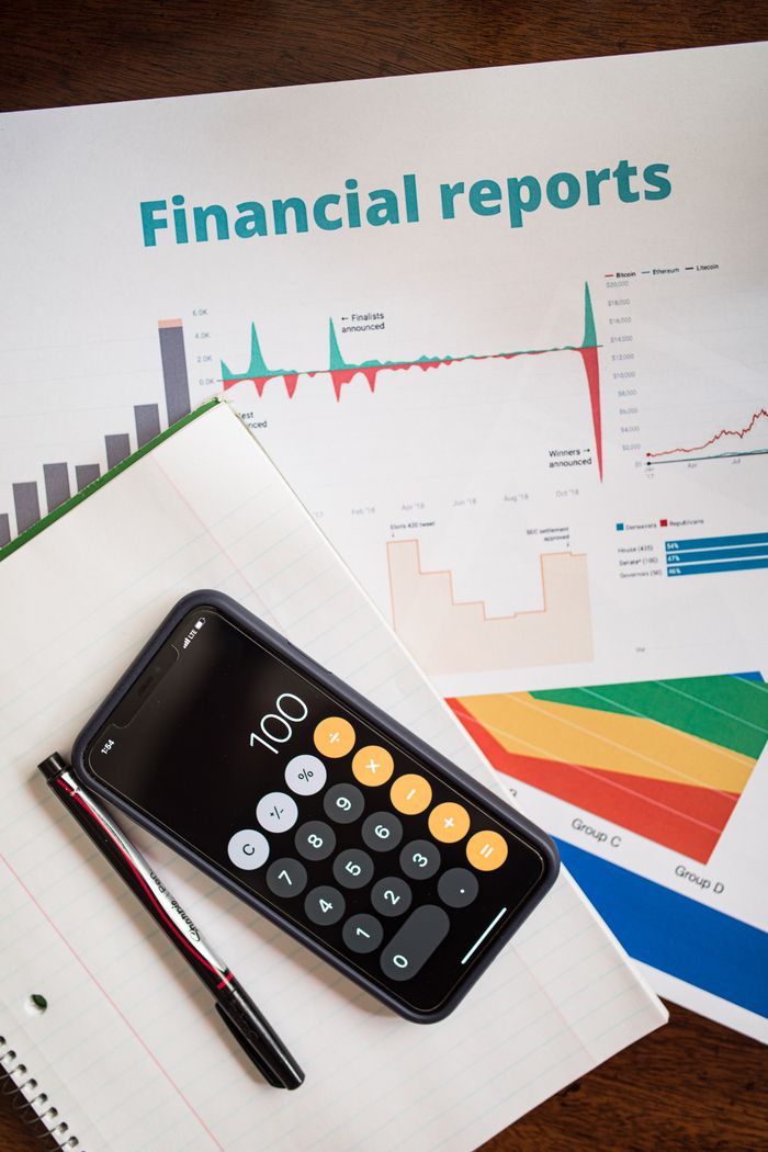 The Art of Drawing Readers In: Your attractive post title goes here Top view of financial reports with a calculator app open on a smartphone.